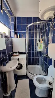 a blue tiled bathroom with a toilet and a sink at Apartment Nataly in Vračar (historical)