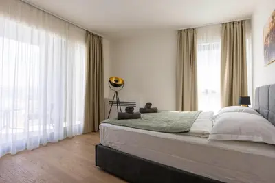 a bedroom with a large bed and large windows at Huge 3 Bedroom Apartment With River View in Belgrade