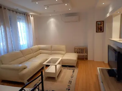 a living room with a white couch and a tv at Matisse Apartment Airport in Ledine
