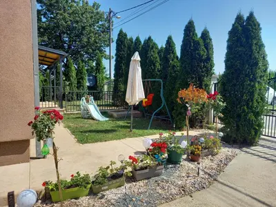 a garden with flowers and an umbrella and a playground at Matisse Apartment Airport in Ledine