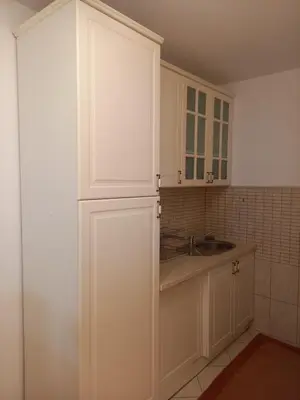 a kitchen with white cabinets and a sink at Matisse Apartment Airport in Ledine
