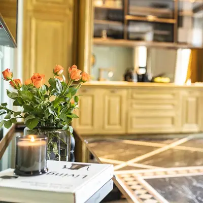 a vase of orange flowers on a counter with a candle at Marconio Luxury city center apartment with own spa zone in Belgrade