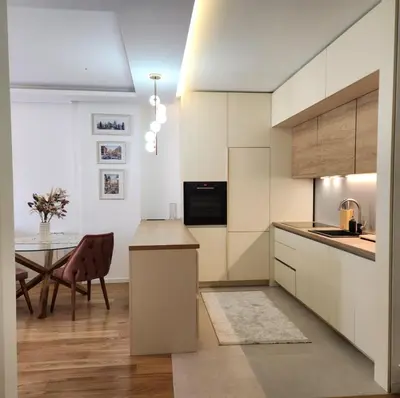 a kitchen with white cabinets and a dining table at APARTMAN FLORENCE in Mirijevo