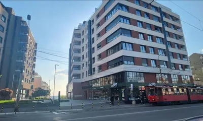 a tall building with a red bus in front of it at APARTMAN FLORENCE in Mirijevo