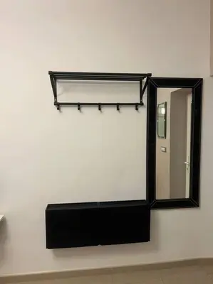 a mirror on a white wall with a black shelf at Sany Center Apartment in Belgrade