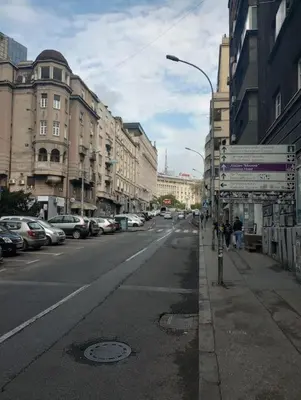 an empty city street with parked cars and buildings at Sany Center Apartment in Belgrade
