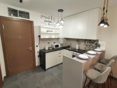 a kitchen with white cabinets and a counter with chairs at Hill Dreams Lux in Belgrade