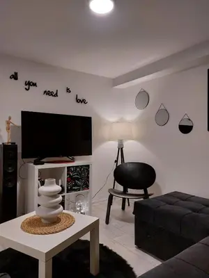 a living room with a flat screen tv and a chair at Bowler Hat Apartment Belgrade in Zvezdara