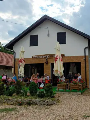 a group of people sitting at a restaurant with umbrellas at Fruškogorski Đeram in Grgeteg