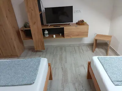 a living room with two beds and a tv at Fruškogorski Đeram in Grgeteg