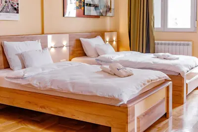 two beds in a room with white sheets at Hotel AirStar in Surčin