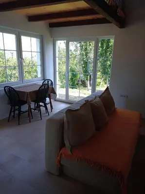 a living room with a couch and a table and windows at Vikendica Smokvica in Sremski Karlovci