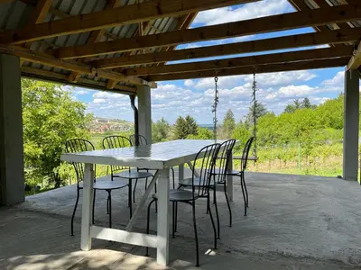 a white table and chairs under a wooden roof at Vikendica Smokvica in Sremski Karlovci